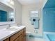 Retro bathroom with blue tile shower, matching accents, and a vanity with a sink at 832 Wildwood Cir, Port Orange, FL 32127