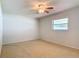Neutral carpeted bedroom featuring a ceiling fan and a window letting in natural light at 832 Wildwood Cir, Port Orange, FL 32127