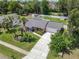 Aerial view features the home's manicured front yard, long driveway, and attractive landscaping with mature palm trees at 832 Wildwood Cir, Port Orange, FL 32127
