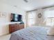 Comfortable bedroom with a large television above the dresser and natural light through curtained windows at 918 Noble Run, New Smyrna Beach, FL 32168
