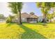 Exterior view of back of home and screened-in porch, landscaped backyard with large trees at 929 N Lakewood Ter, Port Orange, FL 32127