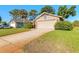 A tan colored home featuring a two-car garage, a clean driveway, and a green lawn at 929 N Lakewood Ter, Port Orange, FL 32127