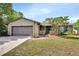 Charming single-story brick home featuring a well-maintained lawn and attached garage, creating a cozy curb appeal at 953 Tulip St, Deltona, FL 32725