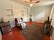 Simple bedroom with a red, cushioned chair, side shelving, and red stained floors at 1081 Cobblestone Ave, Deltona, FL 32725