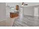 Open-concept living room featuring modern gray wood flooring, ceiling fan, and a view of the kitchen at 1142 Glendale Ave, Deltona, FL 32725