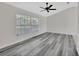 Open living room features a ceiling fan, large window, and stylish gray wood flooring at 1142 Glendale Ave, Deltona, FL 32725