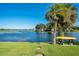 Picturesque waterfront view with lush greenery, palm trees, and a clear blue sky at 1155 E Fowler Dr, Deltona, FL 32725