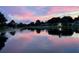 Waterfront homes reflecting a vibrant pink sunset over a tranquil lake create a serene and picturesque scene at 1155 E Fowler Dr, Deltona, FL 32725