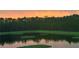 Picturesque pond reflecting the trees under an orange sky at 1183 Cabot Cliffs Dr, Daytona Beach, FL 32124
