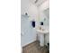 Bright powder room featuring a pedestal sink, decorative shelves, and wood-look tile flooring at 1183 Cabot Cliffs Dr, Daytona Beach, FL 32124