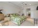 Bedroom with neutral carpeting, ceiling fan, a comfortable bed with a floral pattern, and a view into the hallway at 1209 N Atlantic Ave, New Smyrna Beach, FL 32169