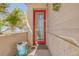 Front door featuring a decorative glass window, and a red frame, complemented by lush greenery and tropical plants at 1209 N Atlantic Ave, New Smyrna Beach, FL 32169