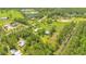 Wide aerial view showcasing a house, barn, and lush green pastures surrounded by lush greenery and mature trees at 140 Rodeo Rd, Ormond Beach, FL 32174