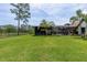 Large backyard with lush greenery featuring a screened-in outdoor area and a manicured lawn, ideal for outdoor living at 160 Point O Woods Dr, Daytona Beach, FL 32114
