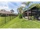 Backyard featuring a screened-in outdoor area with a grill, surrounded by a well-manicured lawn and privacy fence at 160 Point O Woods Dr, Daytona Beach, FL 32114