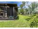 A view of the home's backyard featuring a screened-in outdoor area, lush greenery, and a well-maintained lawn at 160 Point O Woods Dr, Daytona Beach, FL 32114