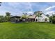 Expansive backyard featuring a screened-in patio with a pool, surrounded by lush greenery and palm trees at 160 Point O Woods Dr, Daytona Beach, FL 32114