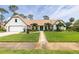 Charming front exterior featuring a well-manicured lawn, lush landscaping, and a brick pathway leading to the front door at 160 Point O Woods Dr, Daytona Beach, FL 32114