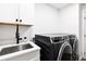 Laundry room featuring a deep sink, white cabinetry, and sleek black washer and dryer at 160 Point O Woods Dr, Daytona Beach, FL 32114