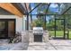Outdoor kitchen featuring a built-in grill, stone counter, and a covered screened-in enclosure for outdoor cooking at 160 Point O Woods Dr, Daytona Beach, FL 32114