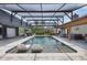 A spacious screened-in pool area featuring lounge chairs, a jacuzzi, and an entertainment center with a TV and projector at 160 Point O Woods Dr, Daytona Beach, FL 32114