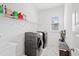 Bright laundry room with modern black appliances, shelving, and marble-style flooring at 16241 Honey Harvest St, Winter Garden, FL 34787