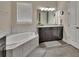 Bathroom featuring a soaking tub, dark wood cabinets, granite counters and decorative mirror at 171 Birchmont Dr, Deland, FL 32724