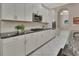 Bright kitchen featuring white cabinets, granite countertops, stainless steel appliances, and white tiled floors at 171 Birchmont Dr, Deland, FL 32724