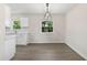 Bright dining area features gray flooring and a modern light fixture, adjacent to a clean white kitchen at 2106 Umbrella Tree Dr, Edgewater, FL 32141