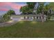 Charming one-story home with brick facade, attached garage, and a lush green lawn under a colorful sky at 2106 Umbrella Tree Dr, Edgewater, FL 32141