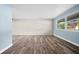 An empty living room featuring a whitewashed brick wall, light wood floors, and a large window at 2226 Sherwood Dr, South Daytona, FL 32119