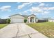 Single-story home boasts an attached garage, manicured front yard, and covered entry, under a sunny sky at 2884 Sweet Springs St, Deltona, FL 32738