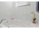 An inviting white bathtub with white tile and an orchid in a decorative vase at 2916 Meleto Blvd, New Smyrna Beach, FL 32168