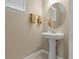 Compact powder room with a pedestal sink, round mirror and neutral walls at 2916 Meleto Blvd, New Smyrna Beach, FL 32168
