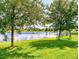Lush green backyard with a serene lake view framed by mature trees, perfect for outdoor activities at 2919 Sime St, New Smyrna Beach, FL 32168