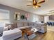 Comfortable living room with a sectional sofa, wood-look flooring, a ceiling fan, and access to the dining area and kitchen at 2919 Sime St, New Smyrna Beach, FL 32168
