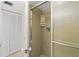 Shower room with glass door, tile surround, and shelving unit at 2987 S Atlantic # 1403, Daytona Beach Shores, FL 32118