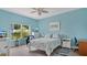 Comfortable bedroom features bright blue walls, ceiling fan, and views to lush greenery outside at 302 Tammie Sue Ln, Deland, FL 32724