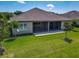 Home's back exterior featuring a screened lanai and well-maintained lawn and landscaping at 3148 Bailey Ann Dr, Ormond Beach, FL 32174