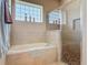 Bright bathroom with soaking tub, glass block window, and updated walk-in shower with pebble floor at 3148 Bailey Ann Dr, Ormond Beach, FL 32174