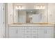 Bright bathroom featuring double sinks, granite countertops, white cabinets and a large mirror at 3402 Torre Blvd, New Smyrna Beach, FL 32168