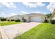 Single-story home featuring a two car garage, manicured shrubs, and a brick paved driveway at 3402 Torre Blvd, New Smyrna Beach, FL 32168
