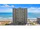 Exterior shot of condo building near the beach with the ocean view in the background and a parking lot at the bottom at 3425 S Atlantic Ave # 1602, Daytona Beach, FL 32118