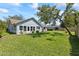 Well-maintained backyard with lush green grass, mature shade tree and a charming house at 35 China Moon Dr, Ormond Beach, FL 32174