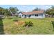 Spacious backyard featuring a lush lawn, a garden bed, mature trees, and a gray house at 35 China Moon Dr, Ormond Beach, FL 32174