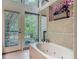 Soaking tub with tile surround and a garden view, perfect for relaxation in a light-filled bathroom at 4073 N Chinook Ln, Ormond Beach, FL 32174