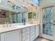 Bright bathroom featuring double sinks, white cabinets, quartz countertops, and a large mirror with track lighting at 4073 N Chinook Ln, Ormond Beach, FL 32174