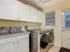 Laundry room featuring modern washer and dryer units, storage cabinets, and natural light at 4073 N Chinook Ln, Ormond Beach, FL 32174