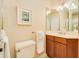 This bathroom features a wood vanity, framed mirror and a picture above the toilet at 4427 S Atlantic Ave, Port Orange, FL 32127