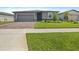 Well-manicured front yard and brick driveway leading to the charming single-story home with a gray exterior at 460 Sarah Nicole Way, New Smyrna Beach, FL 32168